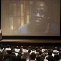 Crowd watches a presentation on a large projector screen